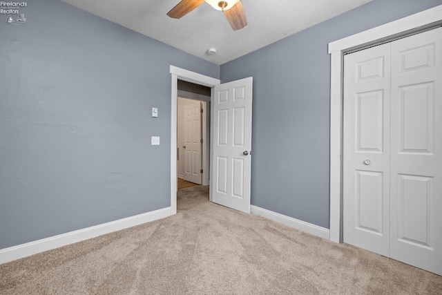 unfurnished bedroom with a textured ceiling, a closet, ceiling fan, and light colored carpet