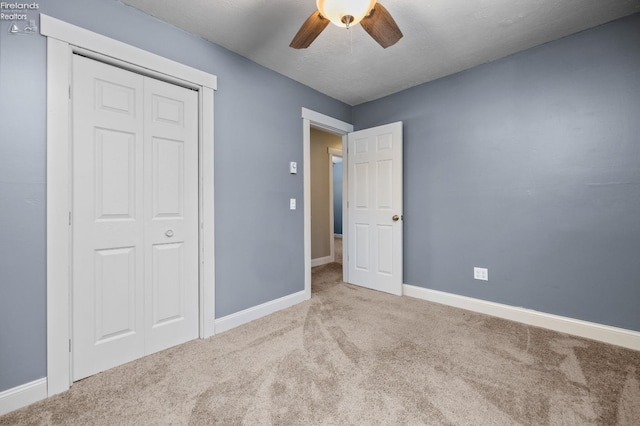 unfurnished bedroom featuring ceiling fan, light colored carpet, a textured ceiling, and a closet