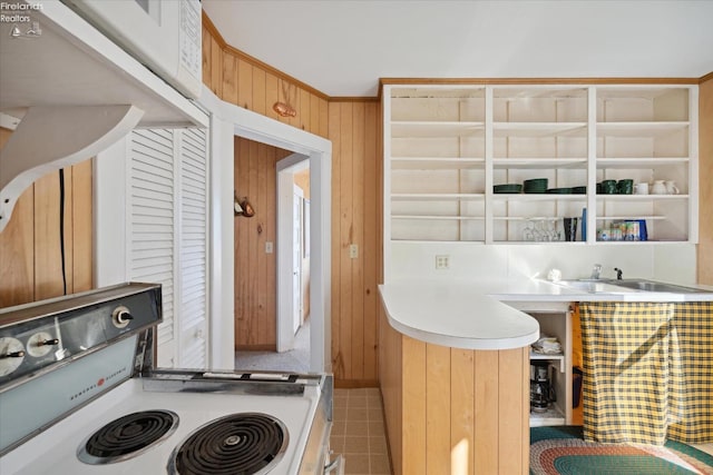 kitchen with wood walls, sink, tile patterned flooring, and white range oven