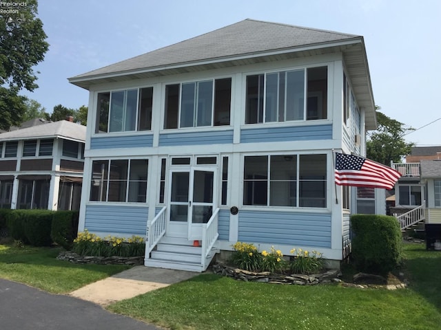 218 Lakefront, Lakeside, OH 43440 - view of front of house with a sunroom, a shingled roof, and a front yard
