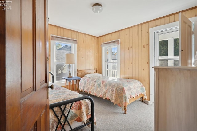 carpeted bedroom with crown molding and wooden walls