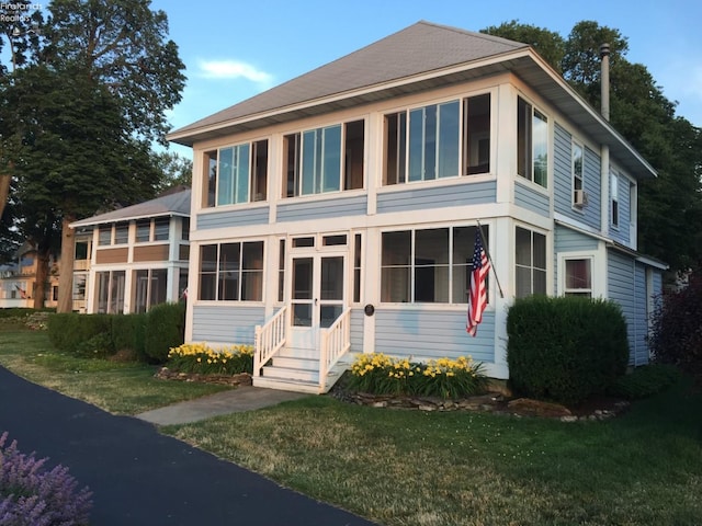 view of front of property featuring a front lawn and a sunroom