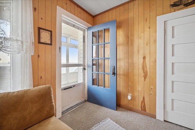 entryway featuring wood walls, carpet floors, and crown molding