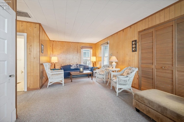 living room with wooden walls, crown molding, and carpet floors