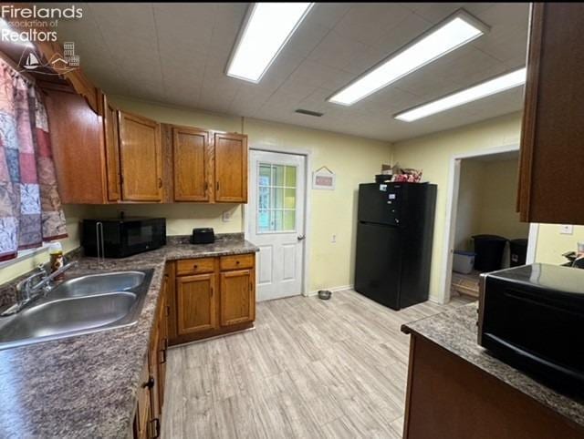 kitchen featuring sink, light hardwood / wood-style floors, and black appliances