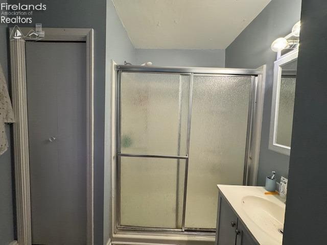 bathroom with a shower with shower door and vanity