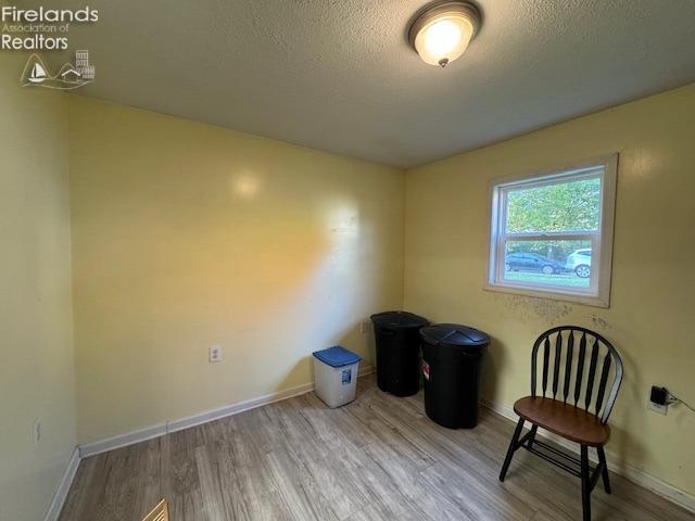 unfurnished room with a textured ceiling and hardwood / wood-style floors