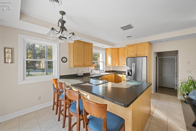 kitchen with kitchen peninsula, decorative light fixtures, stainless steel fridge with ice dispenser, and plenty of natural light