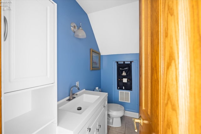 bathroom featuring vanity, lofted ceiling, toilet, and tile patterned floors