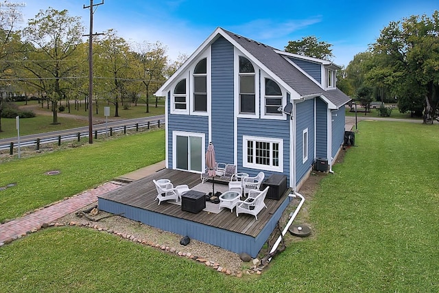 rear view of house with cooling unit, a deck, and a lawn