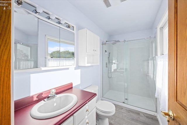 bathroom with hardwood / wood-style flooring, an enclosed shower, toilet, and vanity