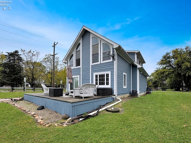 rear view of house with a wooden deck, cooling unit, and a lawn