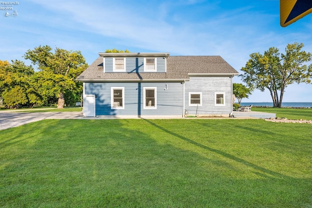 rear view of property with a patio, a lawn, and a water view