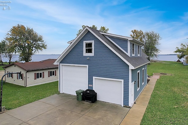 view of property exterior featuring a garage, a lawn, and a water view