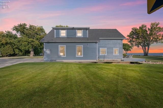 back house at dusk with a lawn