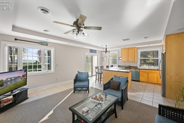 living room with ceiling fan with notable chandelier, light tile patterned floors, and a wealth of natural light