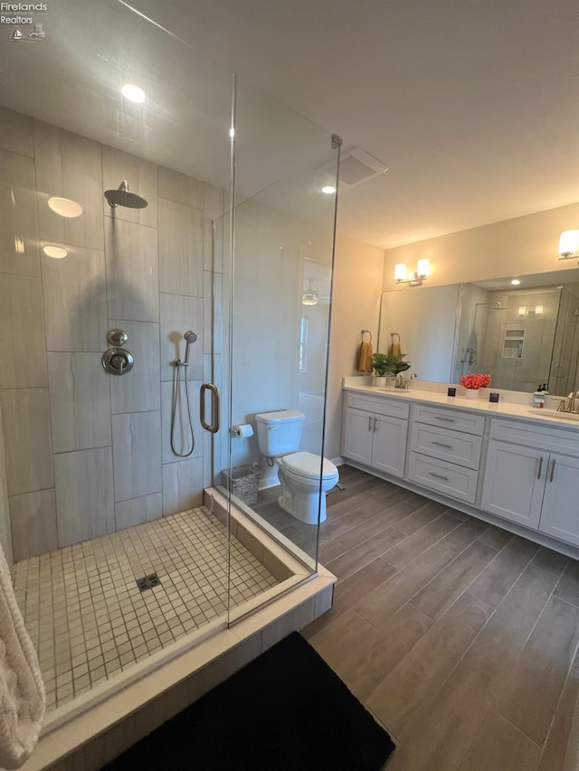 bathroom featuring vanity, wood-type flooring, toilet, and an enclosed shower