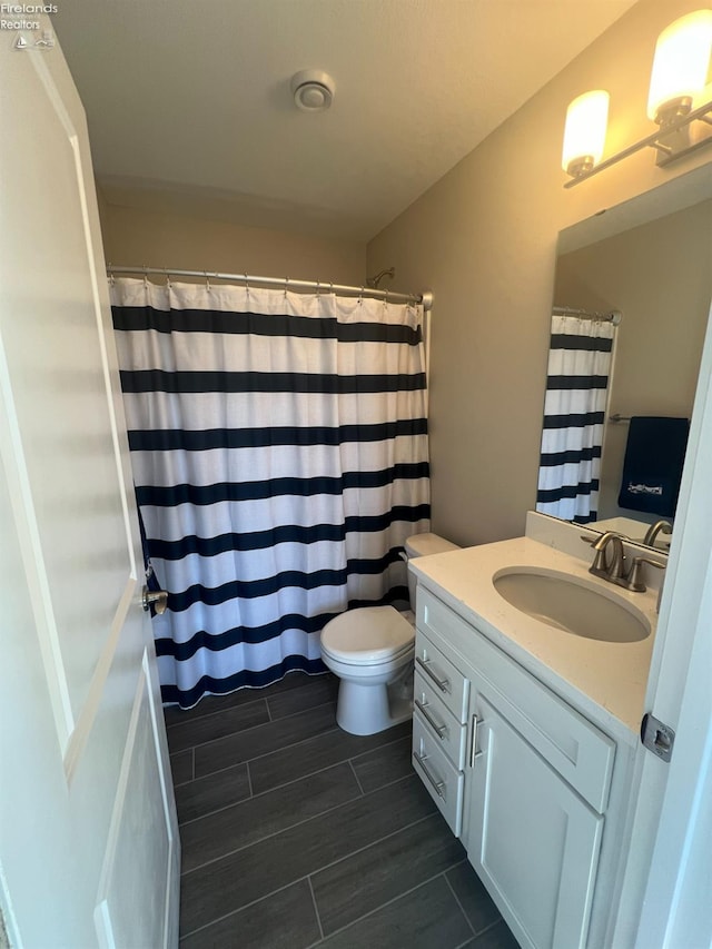 bathroom featuring vanity, curtained shower, and toilet