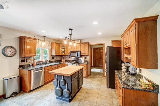 kitchen with pendant lighting, sink, a kitchen island, appliances with stainless steel finishes, and wood counters