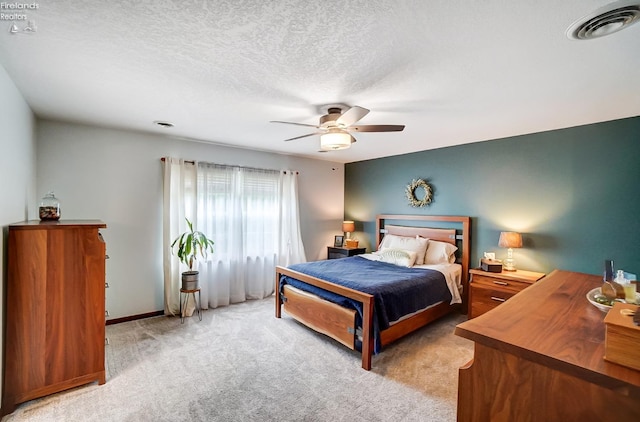 carpeted bedroom with ceiling fan and a textured ceiling