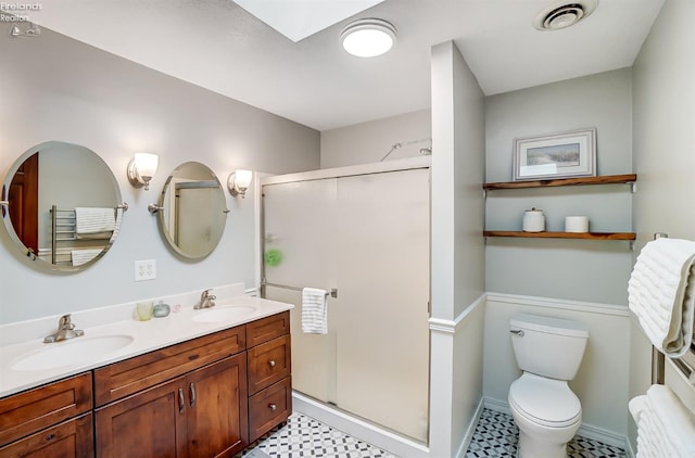 bathroom featuring a skylight, vanity, a shower with door, and toilet