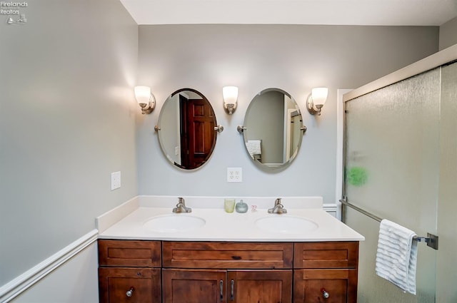 bathroom featuring a shower with door and vanity