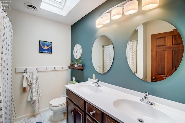 bathroom featuring a skylight, vanity, and toilet