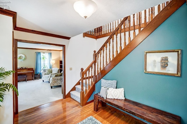 staircase with ornamental molding and hardwood / wood-style flooring