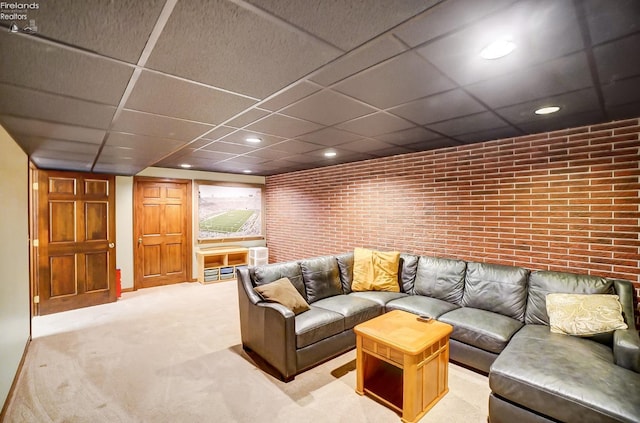 carpeted living room with brick wall and a drop ceiling