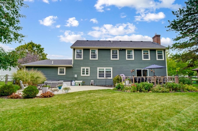 back of house with a deck, a lawn, and a patio area