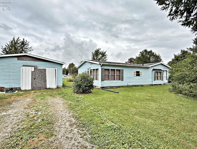 rear view of property featuring a storage shed and a lawn