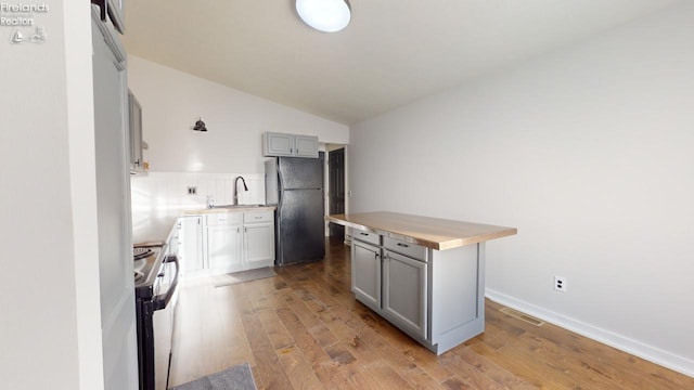 kitchen featuring black fridge, gray cabinetry, a kitchen island, stainless steel electric range, and light hardwood / wood-style floors