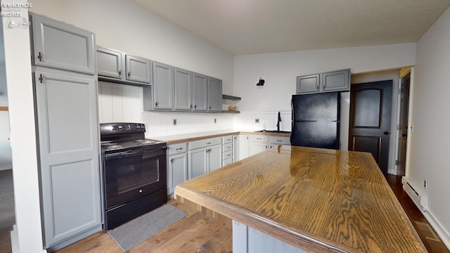 kitchen featuring light hardwood / wood-style floors, sink, gray cabinetry, black appliances, and vaulted ceiling