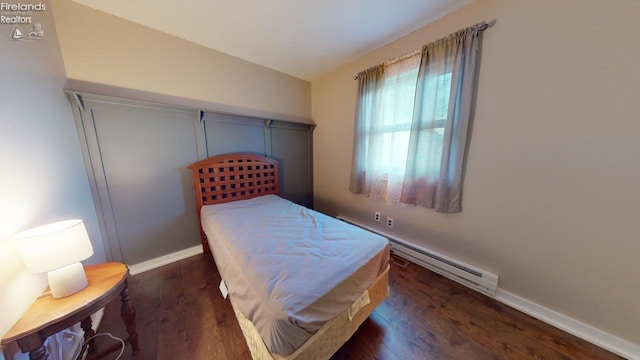 bedroom with a baseboard heating unit and dark hardwood / wood-style flooring