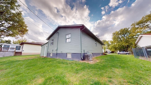 back of house featuring central air condition unit and a lawn