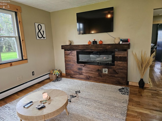 living room featuring wood-type flooring, baseboard heating, and a textured ceiling