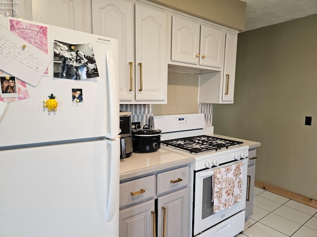 kitchen with a textured ceiling, light tile patterned floors, white appliances, and white cabinetry