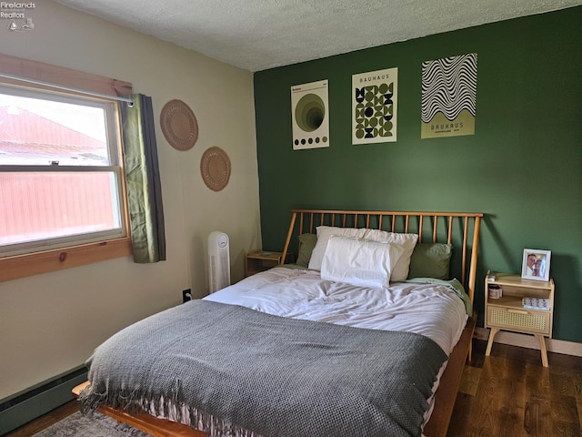 bedroom with a baseboard radiator, dark hardwood / wood-style flooring, and a textured ceiling