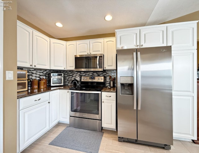 kitchen with backsplash, white cabinets, appliances with stainless steel finishes, and light hardwood / wood-style flooring