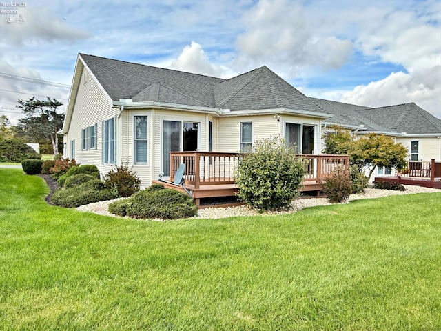 back of property with a wooden deck and a lawn