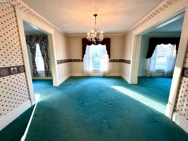 empty room featuring ornamental molding, a chandelier, a textured ceiling, and carpet flooring