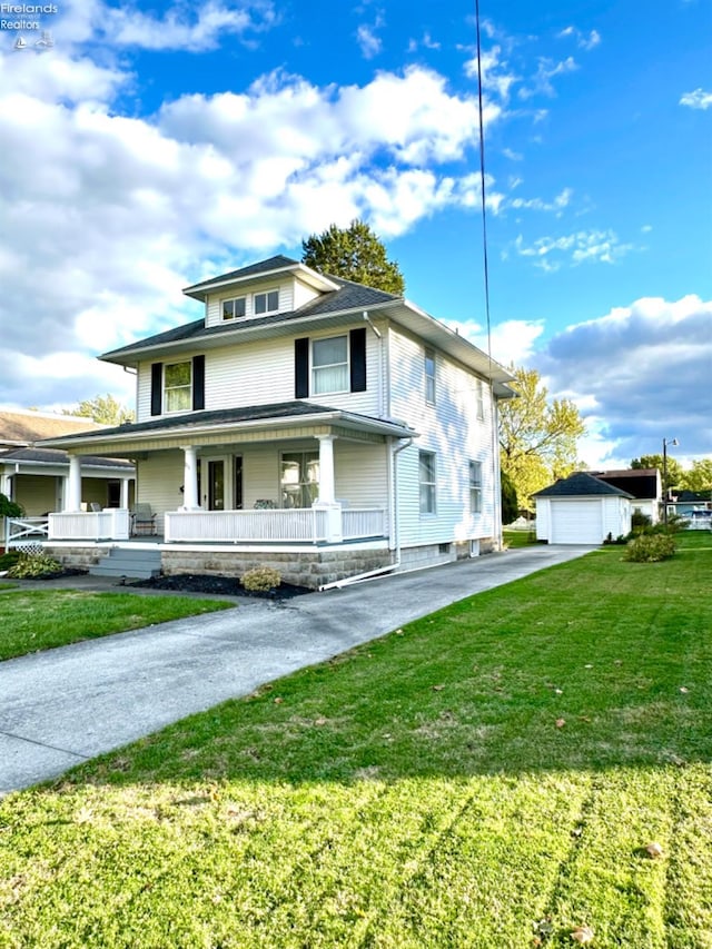 view of front of home with a porch, a front lawn, an outbuilding, and a garage