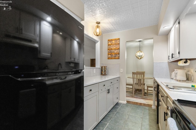 kitchen featuring stainless steel range, hanging light fixtures, black refrigerator, backsplash, and white cabinetry