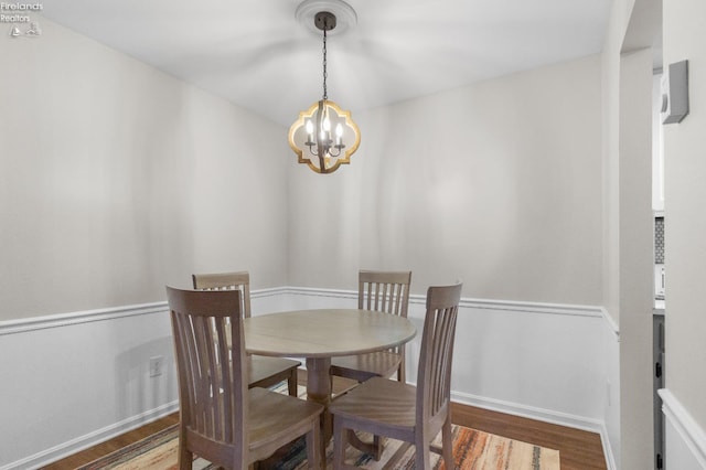 dining area with hardwood / wood-style flooring and an inviting chandelier