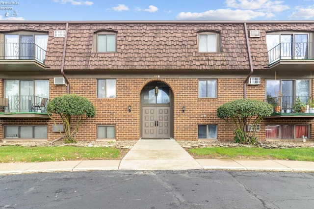 view of property with a wall mounted AC and a balcony