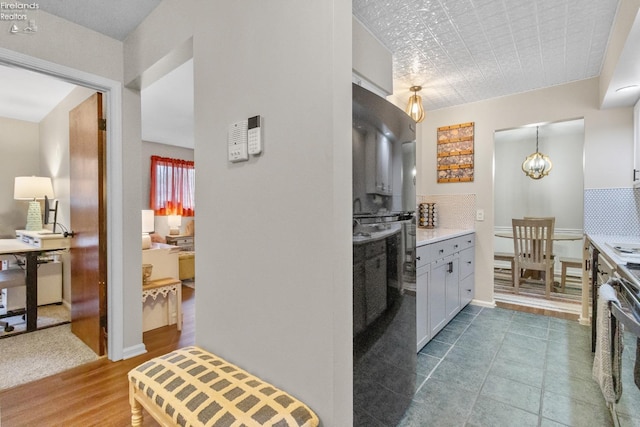 kitchen with hanging light fixtures, hardwood / wood-style floors, black oven, stainless steel stove, and decorative backsplash