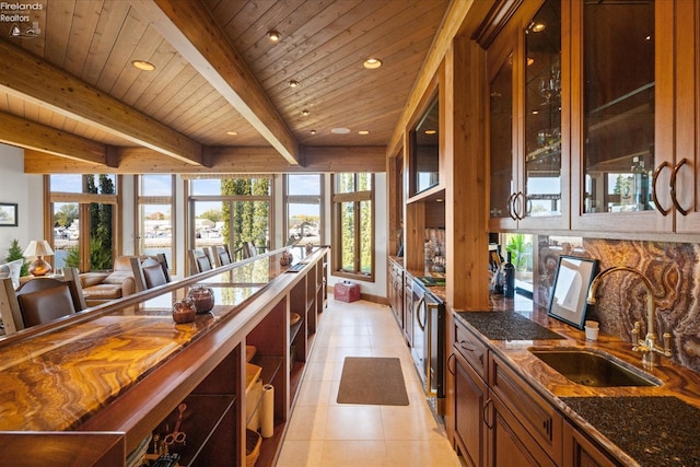 kitchen featuring dark stone counters, sink, wooden ceiling, and plenty of natural light