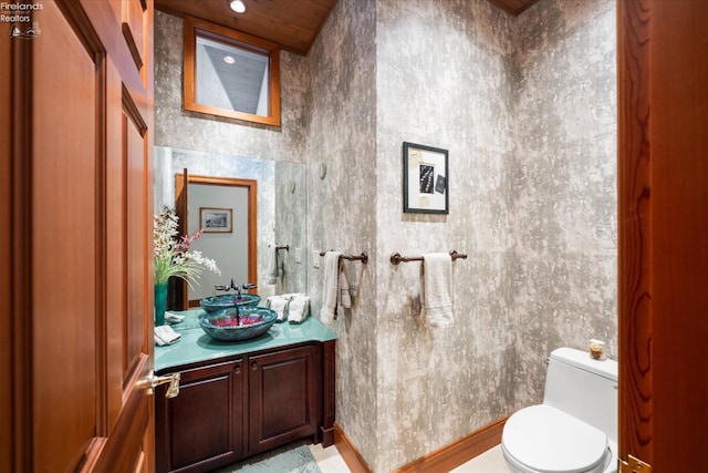 bathroom featuring a towering ceiling, vanity, and toilet