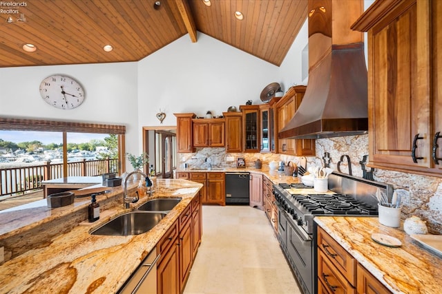 kitchen with decorative backsplash, light stone counters, high end stainless steel range oven, wall chimney exhaust hood, and sink