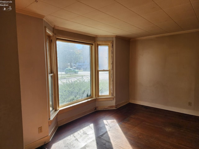 spare room with ornamental molding and dark hardwood / wood-style floors